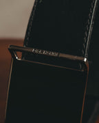 鏡面仕上げのプレートバックル上部に配された、DIOR HOMME刻印のディテールカット。ブラックのベルト本体と両端のステッチも確認できます。
