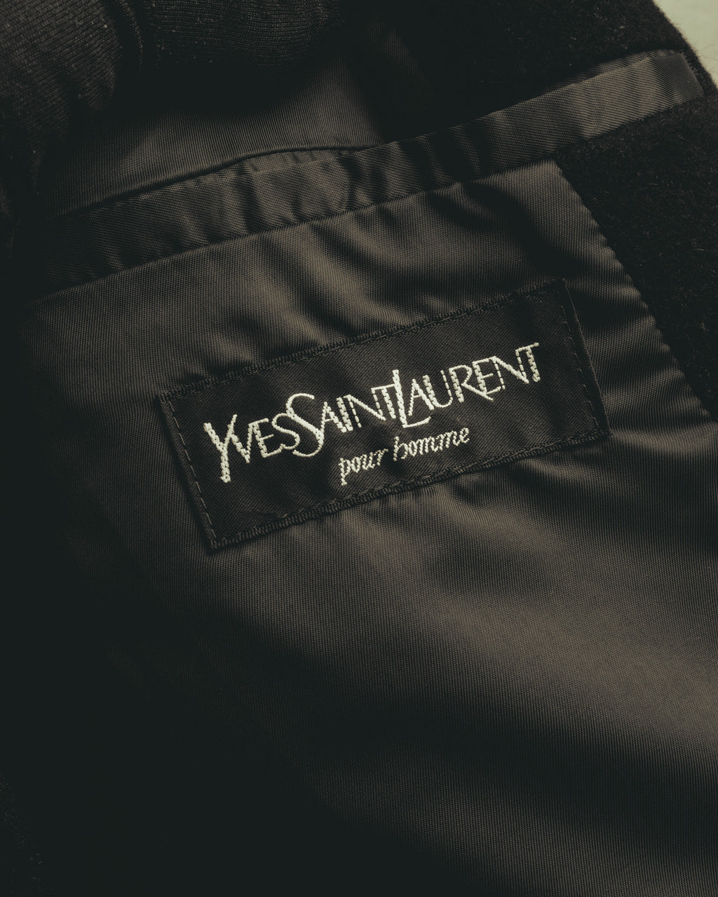 総裏仕立ての内側に縫い付けられた「YVES SAINT LAURENT pour homme」表記の内タグ。滑りの良いブラックの裏地とあわせて確認できるカットです。