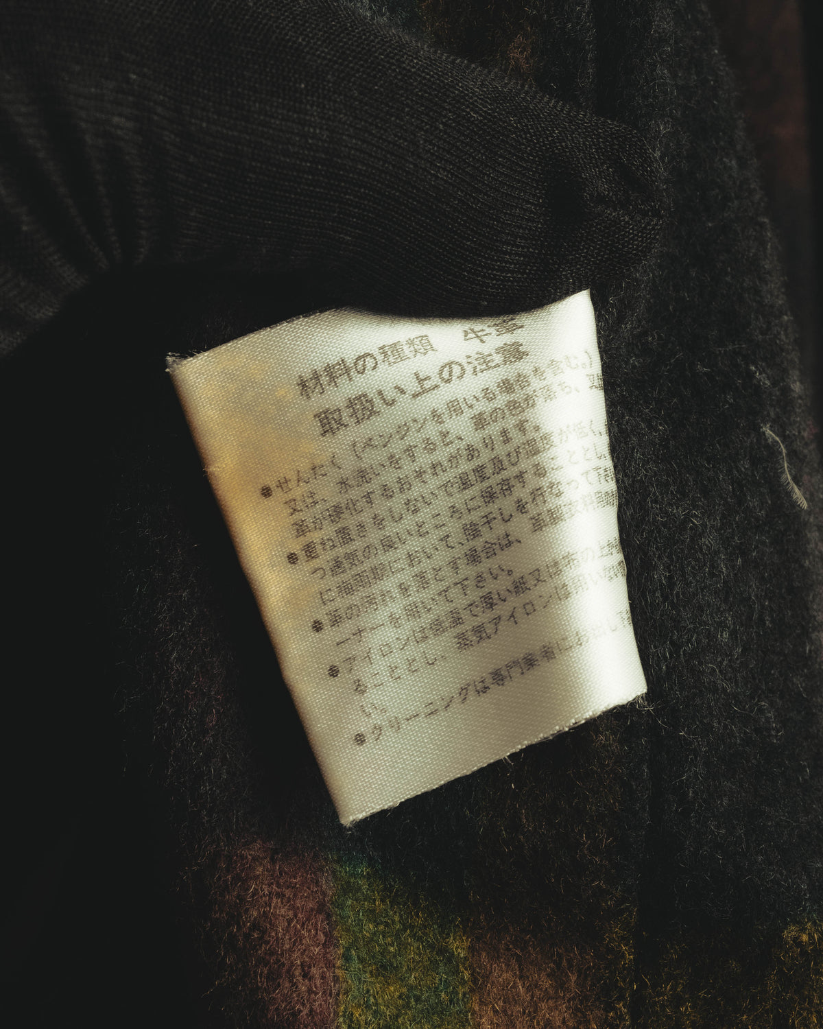 内側の起毛チェック生地に配された、日本語表記のレザー取扱いタグ。現代的な情報表示を伴わないタグのディテールが確認できるカットです。