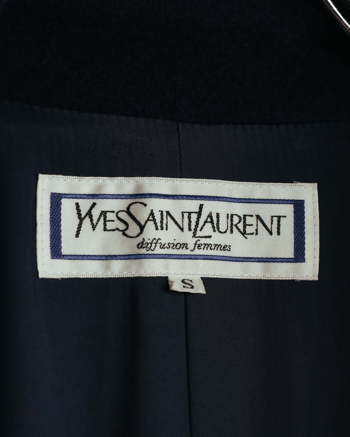 襟元に配された「Yves Saint Laurent diffusion femmes」の織りタグと、S表記のサイズタグを確認できるカット。濃紺の総裏地上にタグが縫い付けられています。