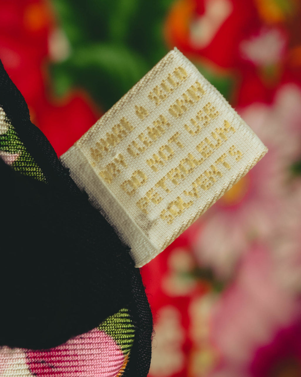生成り色の織りタグに、GUCCI、100% SILK、SOIE、MADE IN ITALYおよび法令表記が確認できるタグのクローズアップ。