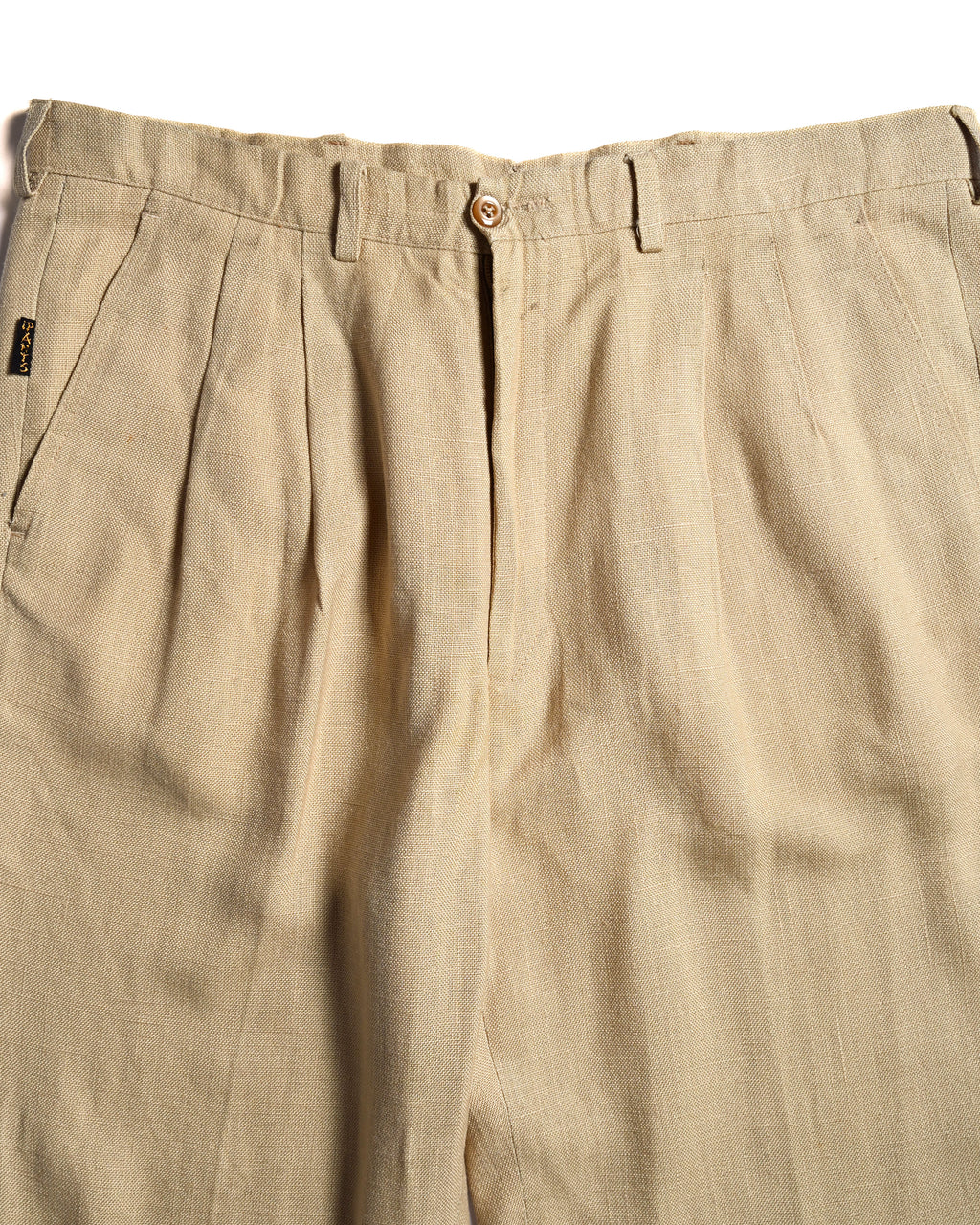ウエスト周りに施された深めの2タックと、サイドポケット横の小ぶりな「i Pants」タブを捉えたディテールカット。ライトベージュのリネンブレンド生地の織り感も確認できます。