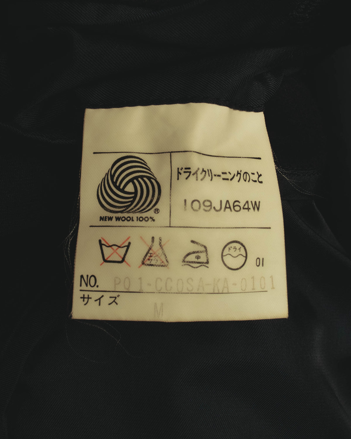NEW WOOL 100%表記と旧式の日本語取扱絵表示が確認できる、内側の品質表示タグ。表記サイズはM。