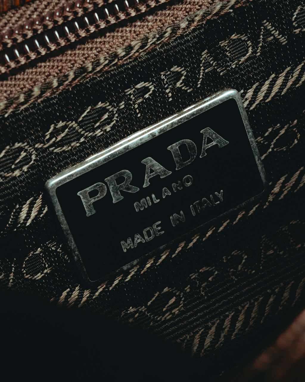 内装に配された「PRADA MILANO MADE IN ITALY」刻印入りプレートと、ロープ状モチーフを反復した織りジャカードのディテール。