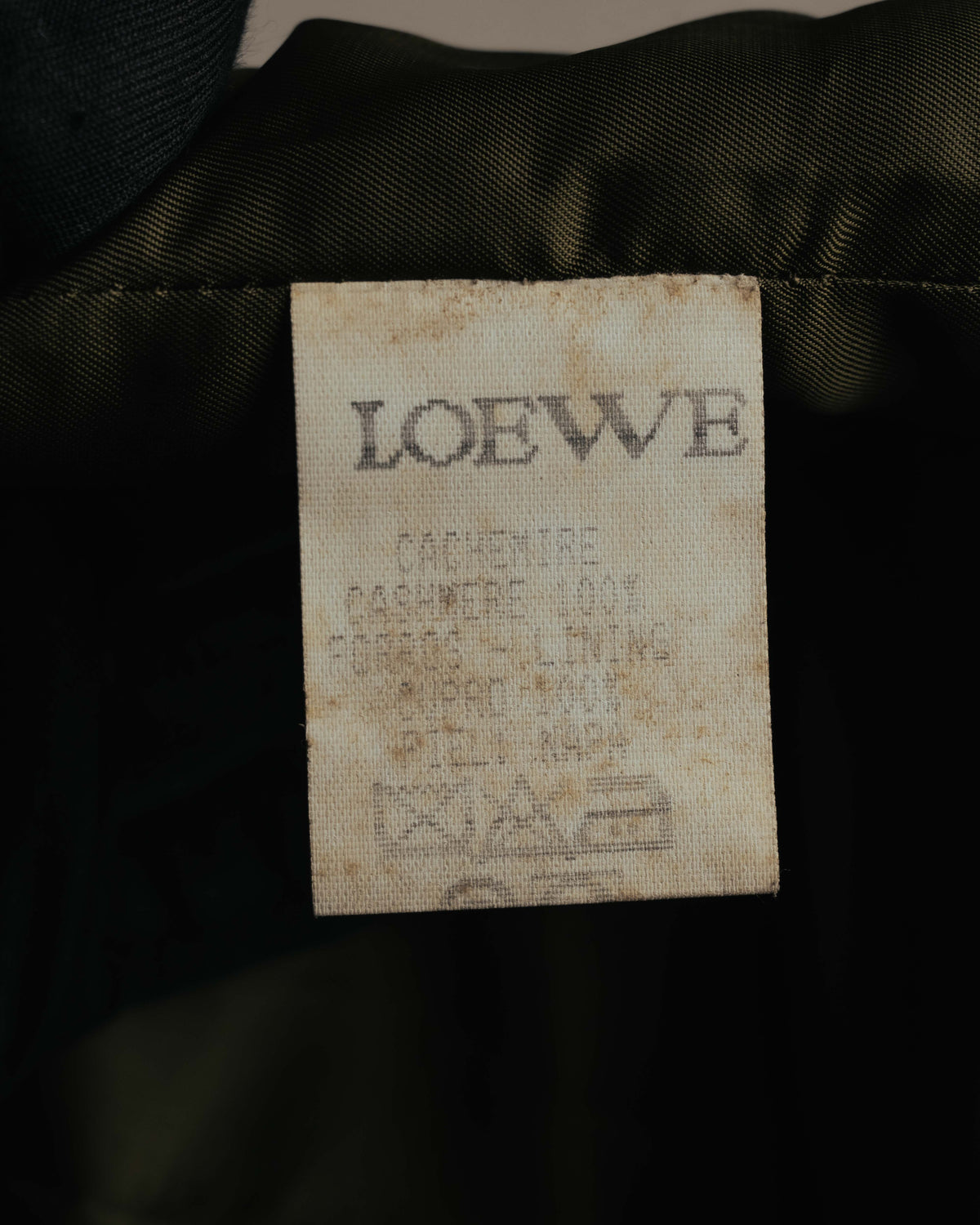首元に配されたLOEWE表記のタグと、下部の品質表示を写したカット。品質表示は退色により一部が判読しづらい状態です。