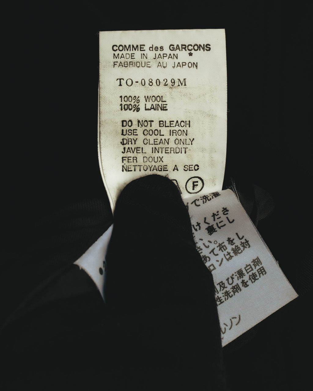 COMME des GARÇONS表記と日本製表記、毛100パーセントの素材表示が確認できる内側の品質表示タグ。旧式の品質表示仕様を捉えたカットです。