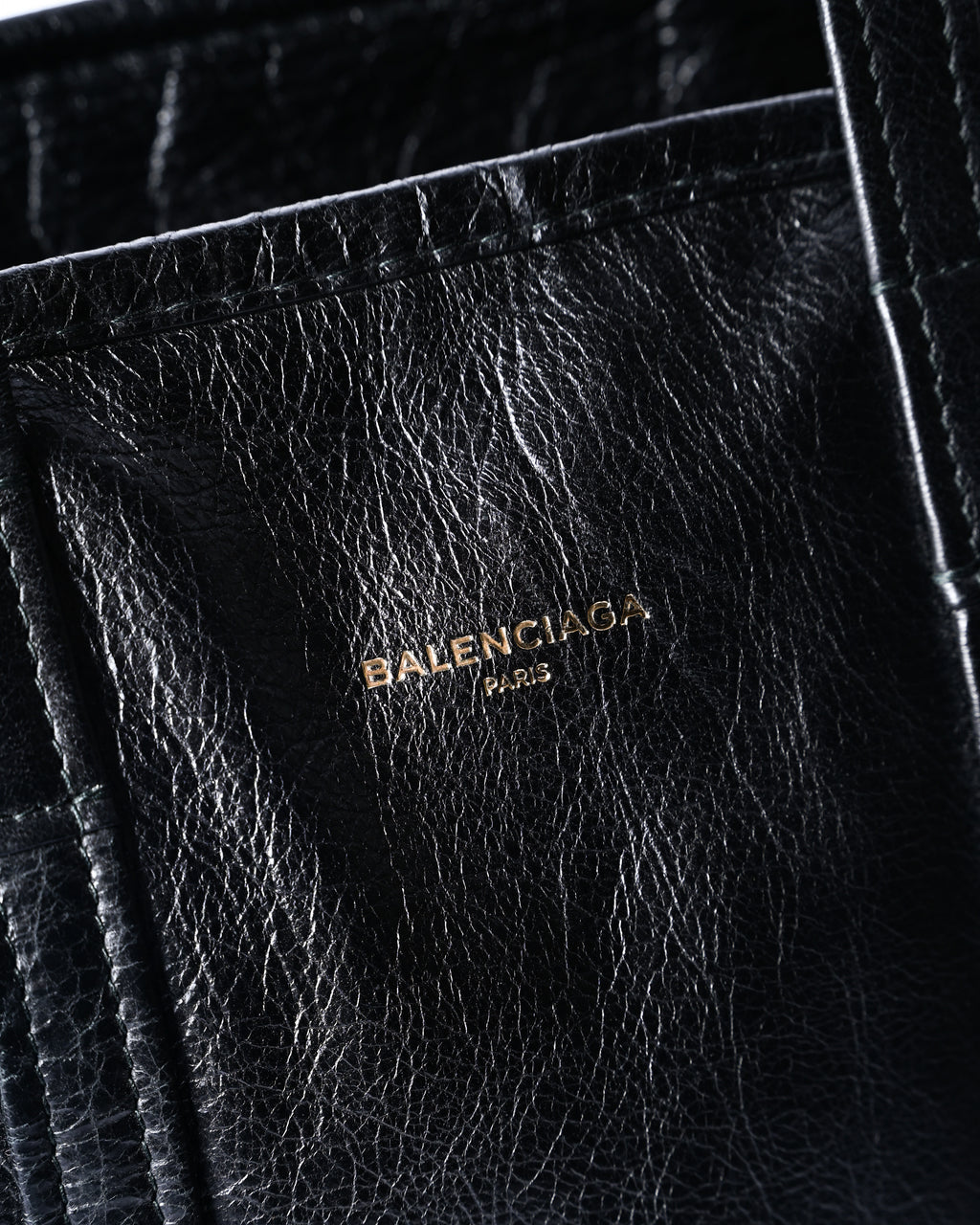 フロント上部にあしらわれた「BALENCIAGA PARIS」の箔押しロゴを捉えたディテールカット。自然なシワ感を備えたブラックレザーの質感も確認できます。