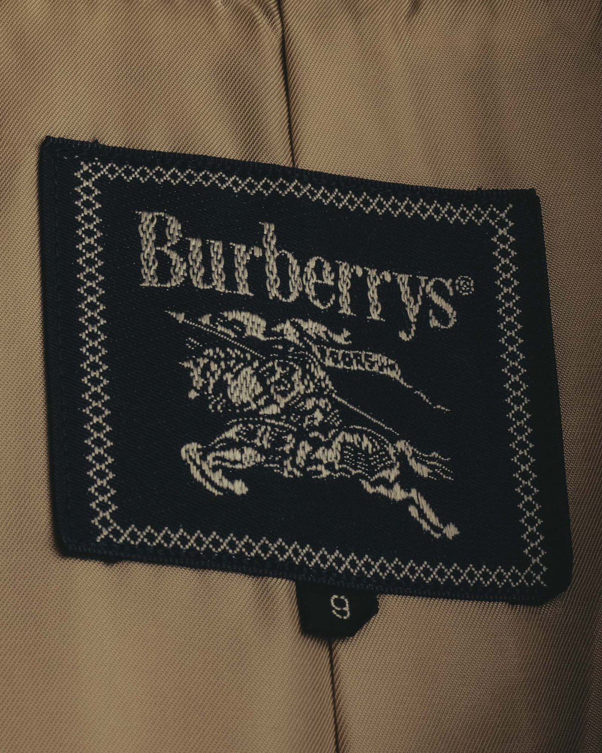 内側の首元に配された、騎士意匠とBurberrys表記を織り込んだブランドタグのカット。下部には表記サイズ9のタグが確認できます。