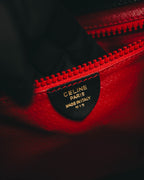鮮烈なレッドの内装に、CELINE PARIS MADE IN ITALY M 13と金色で刻印された黒色の内タグを配したカット。内装ポケット上部には同色の大型樹脂エレメントファスナーが確認できます。
