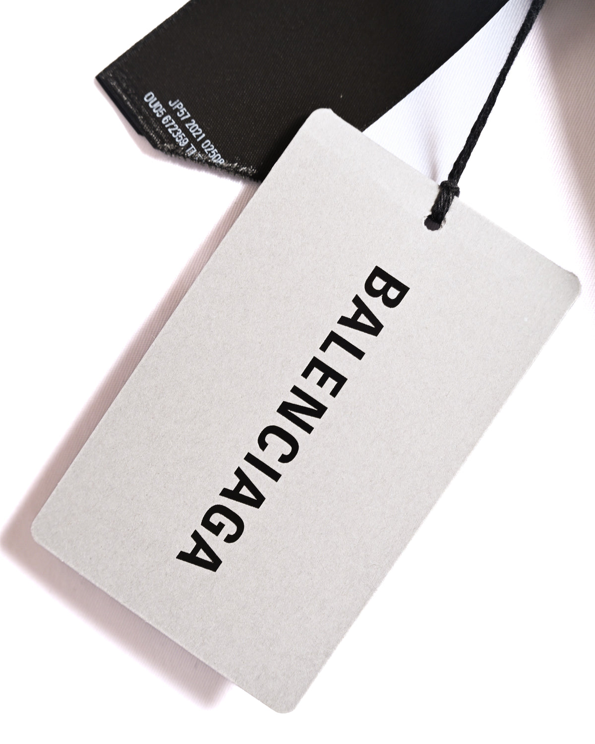 BALENCIAGAロゴを配した下げ札と、品番が印字されたブラックのタグを写したカット。