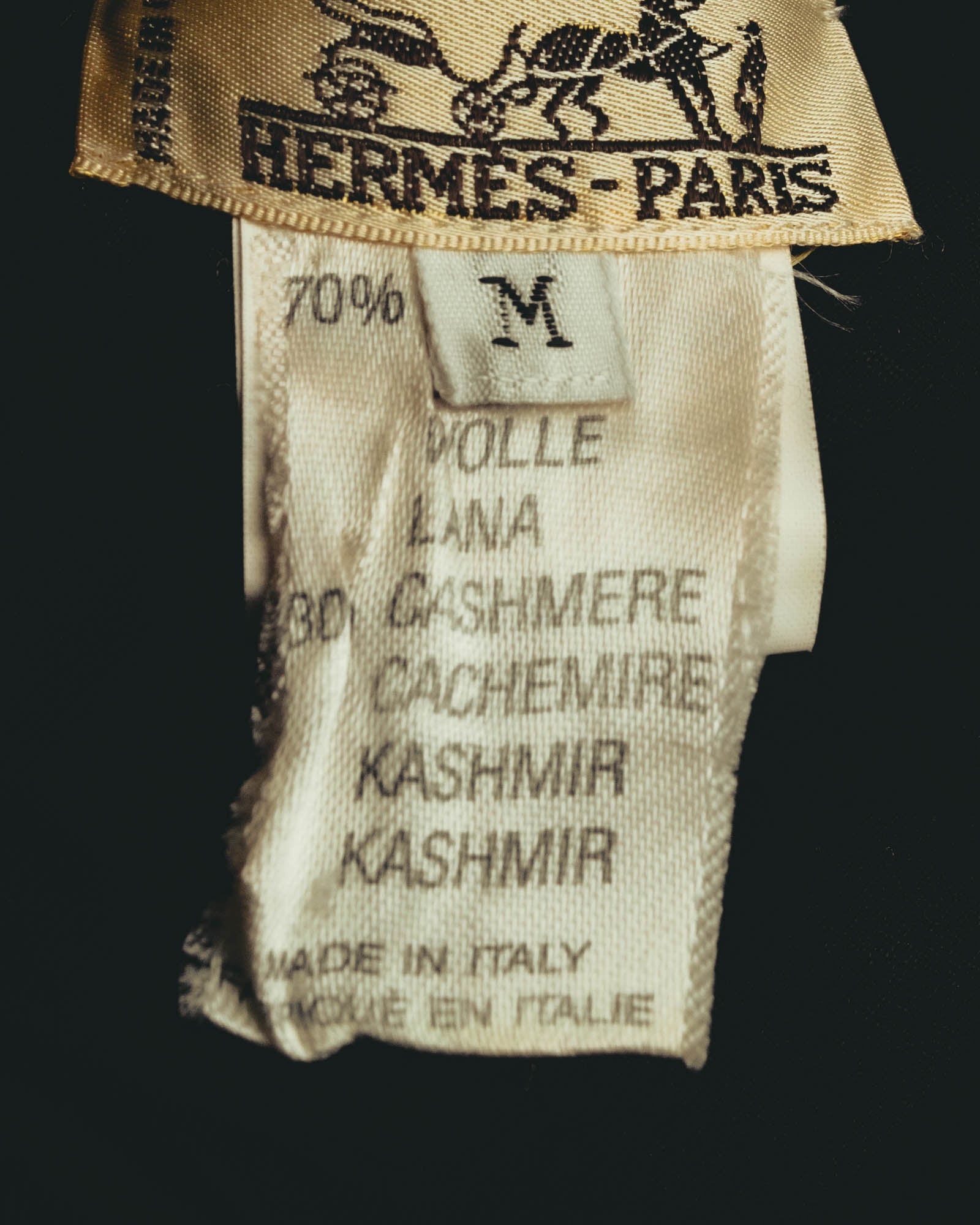 馬車図案とHERMÈS-PARISが入る金色の織りタグ、ならびにウール70％・カシミヤ30％、MADE IN ITALY表記を確認できる内タグのカット。