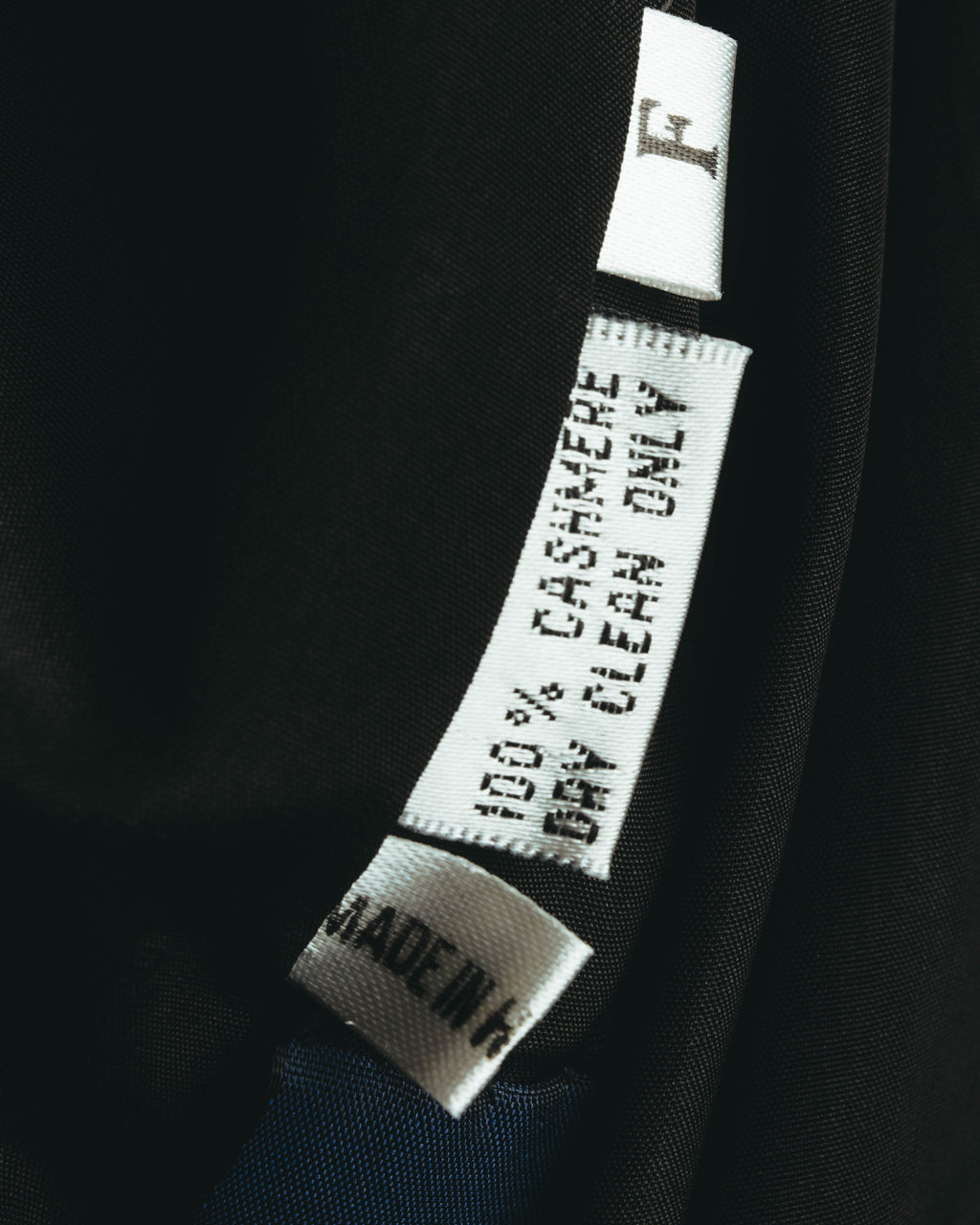 裏地内側に配された品質表示タグのクローズアップ。CASHMERE 100%およびMADE IN H.K.の表記が確認できるカット。