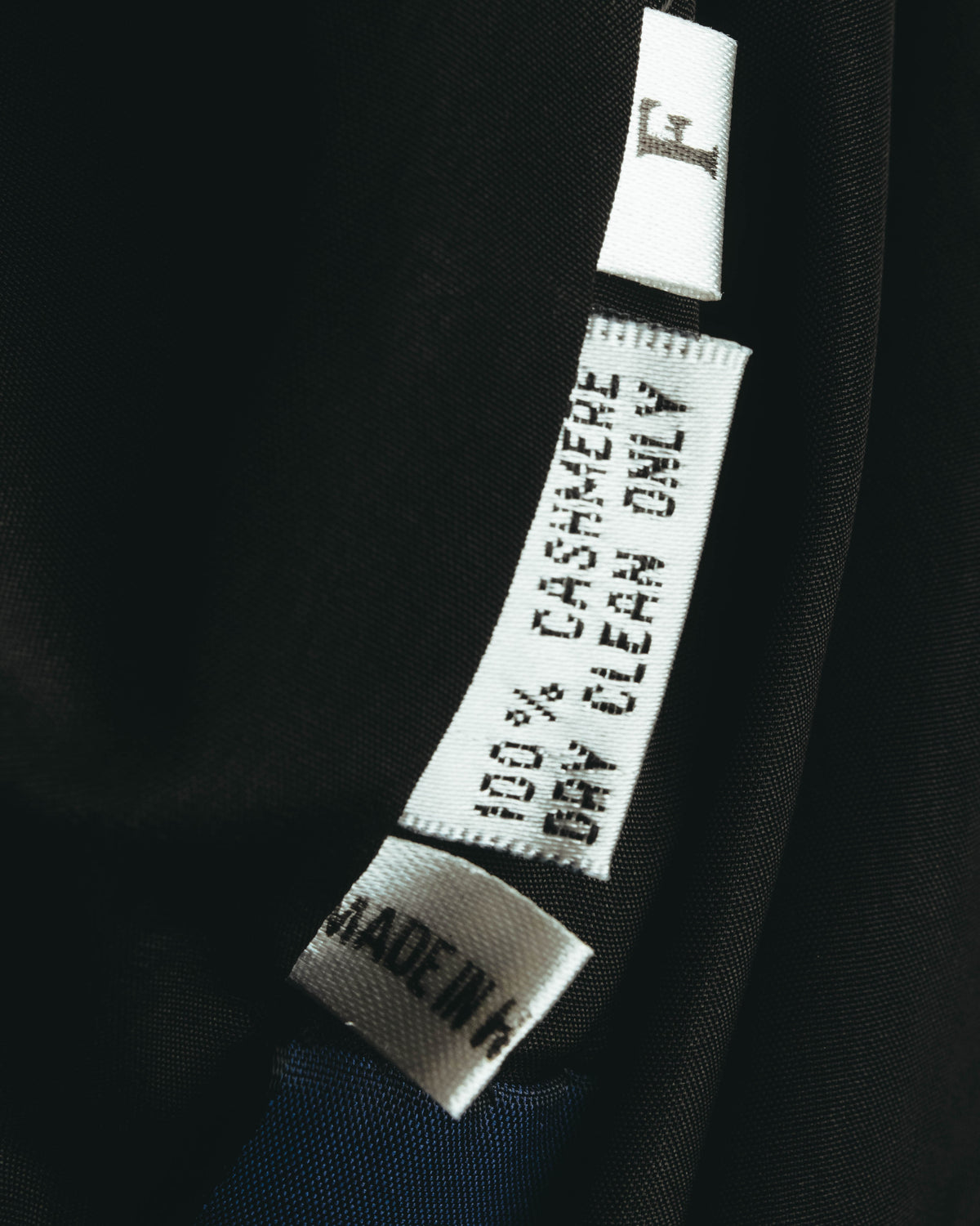 裏地内側に配された品質表示タグのクローズアップ。CASHMERE 100%およびMADE IN H.K.の表記が確認できるカット。