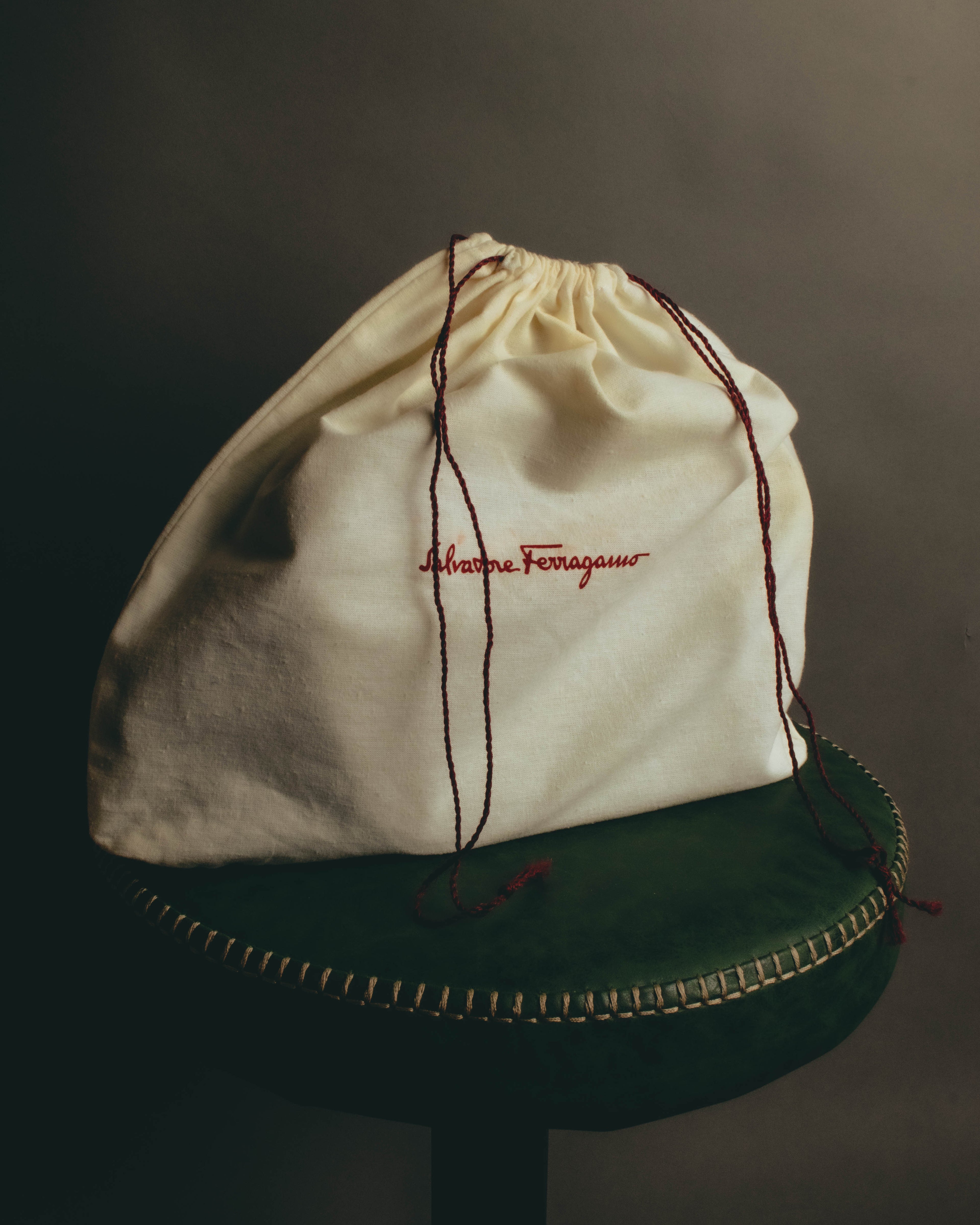 筆記体のSalvatore Ferragamoロゴを赤糸で刺繍した、巾着型の保存袋を写したカット。