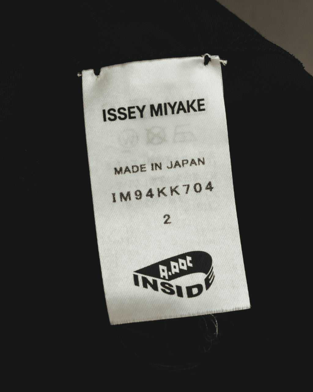 「ISSEY MIYAKE」、MADE IN JAPAN、品番「IM94KK704」、表記サイズ2を確認できる内タグのカット。A-POC INSIDEのロゴも配されています。