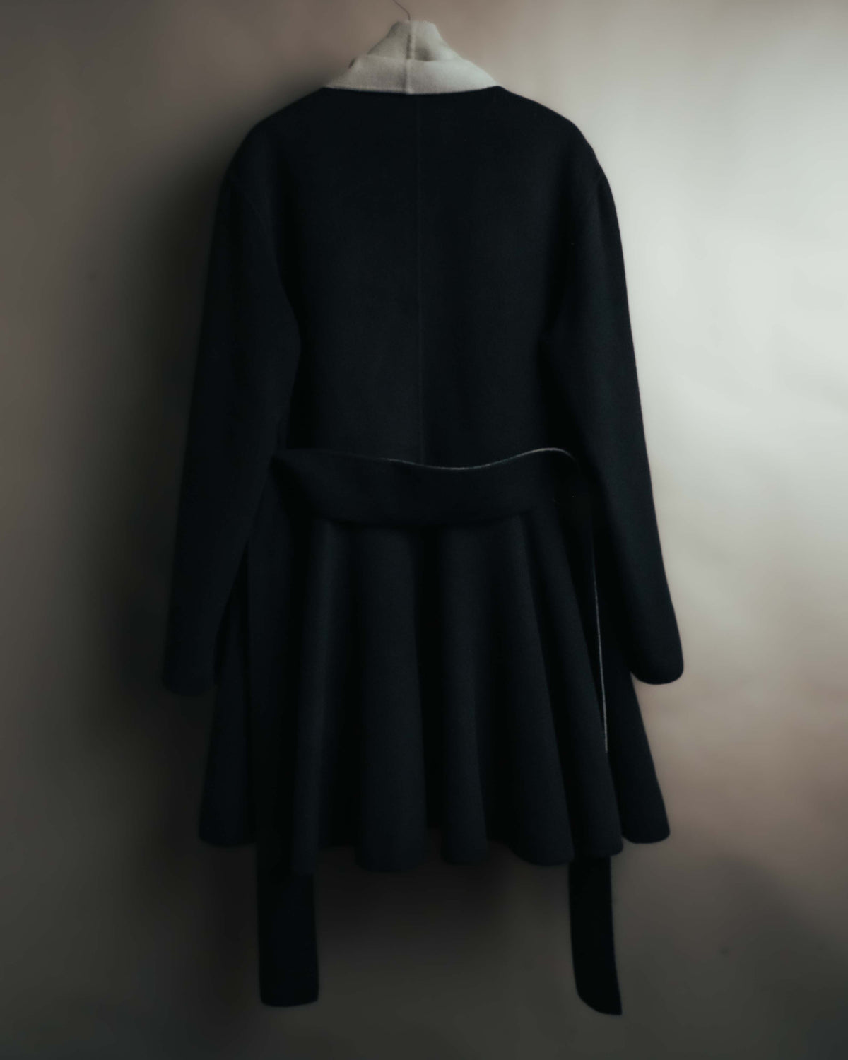 ブラックの身頃を背面から捉えた全体カット。ウエストの共布ベルトと、裾へ向かって広がる量感のあるシルエットが確認できます。