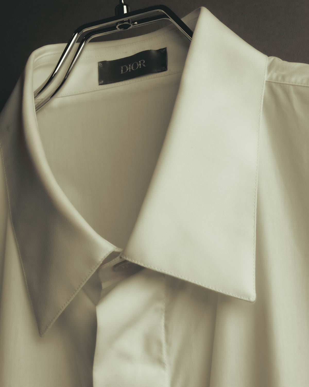 端正な襟元の内側に、全大文字でDIORと記された首裏タグを配したカット。旧来のDior HommeではないDIORタグの表記を確認できます。