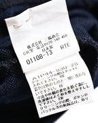 ネイビーニットの内側に付属する品質表示・ケアタグのクローズアップ。クリーニング時の注意書きと品番表記が確認できるカット。