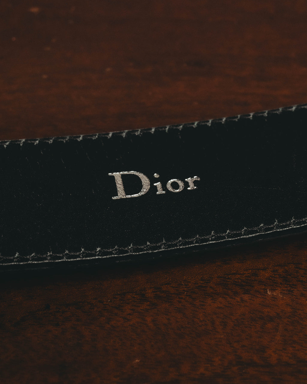 ブラックのベルト内側に銀色で配されたDiorロゴ印字のクローズアップ。縁には両端へ走るステッチが確認できます。