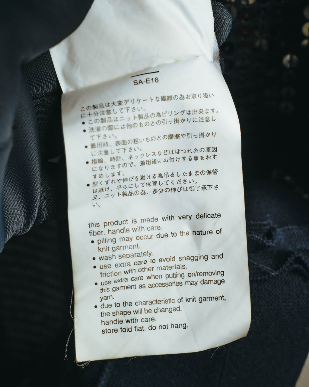 品番「SA-E16」とデリケートなニット製品に関する取り扱い表記が確認できる、旧仕様のケアタグのカット。
