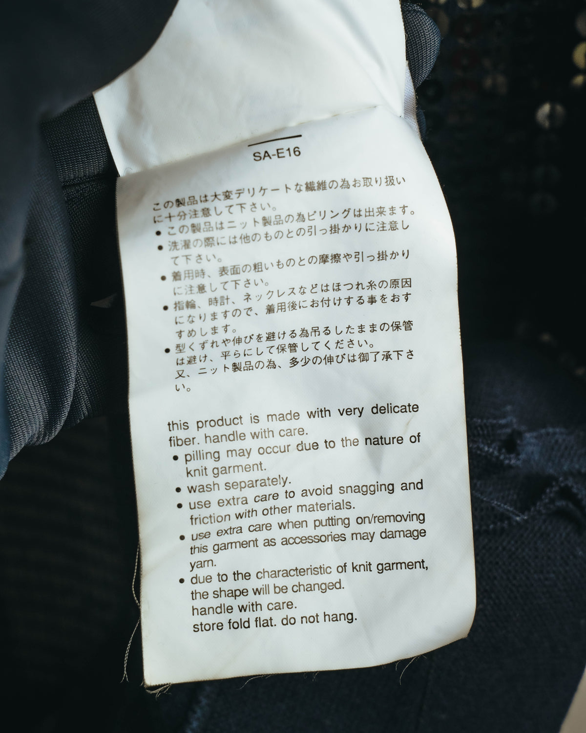 品番「SA-E16」とデリケートなニット製品に関する取り扱い表記が確認できる、旧仕様のケアタグのカット。