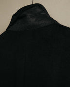 襟元から肩にかけてのブラックカシミヤを捉えた素材アップ。繊細な起毛感と、構築的な肩まわりに加わる柔らかな表情が確認できます。