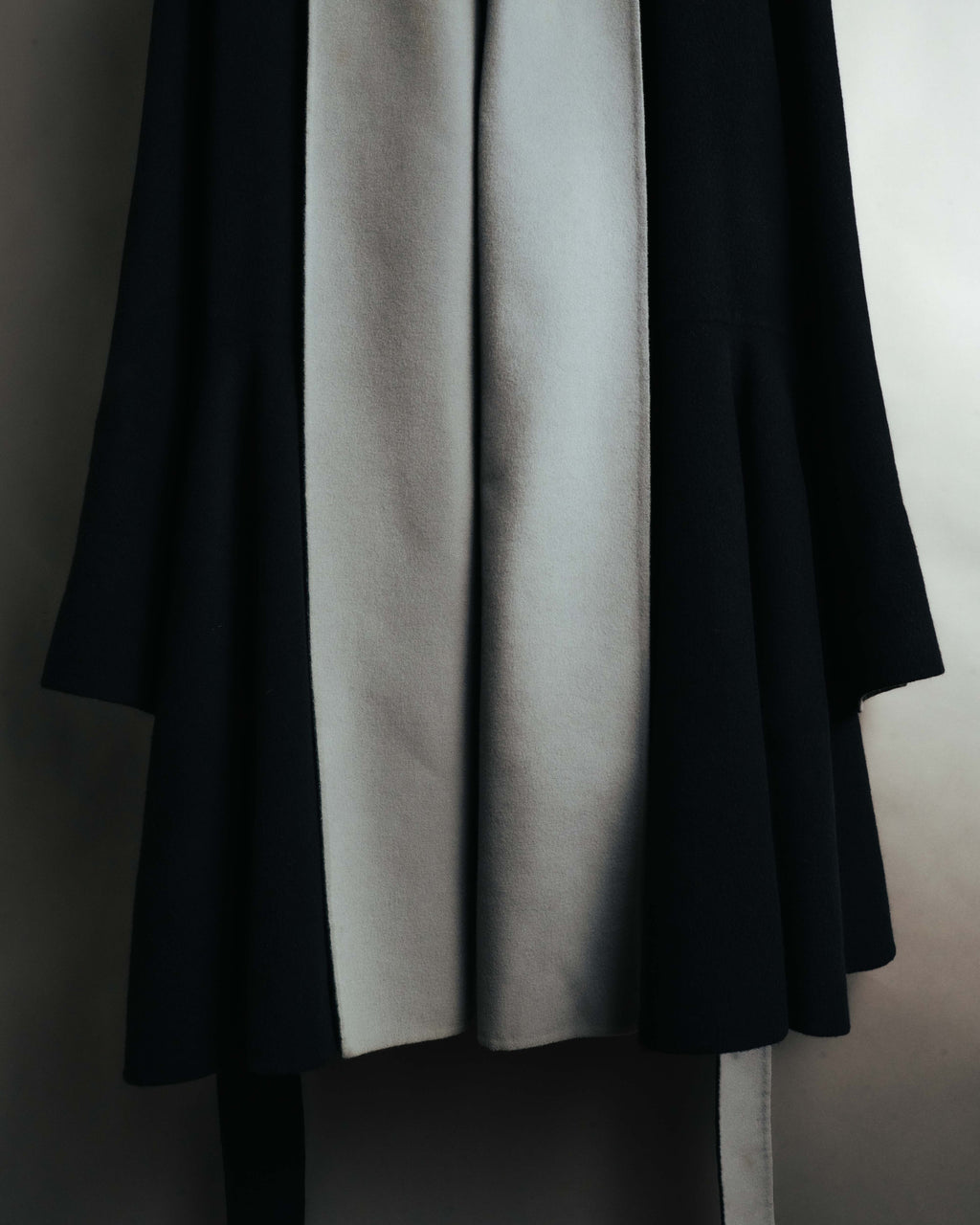 ブラックの身頃に淡いグレーのロングショールカラーが連続するフロントディテール。起毛感のある生地と、裾へ向かう柔らかなドレープが確認できるカット。