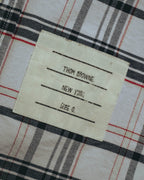 タータンチェックのフロント裾に配された外付けブランドネームのアップ。「THOM BROWNE. NEW YORK.」「Size 0」の表記が確認できる。