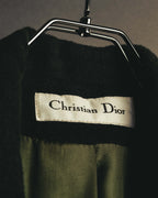 アイボリー地に黒いセリフ体で「Christian Dior」と表記されたネックタグのクローズアップ。周囲には深いダークフォレストグリーンの起毛ウールと総裏地が確認できます。