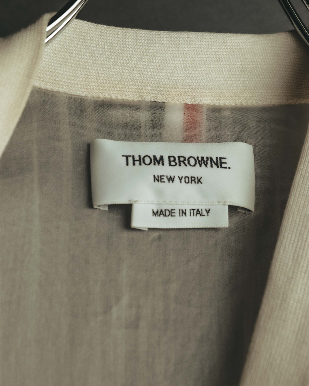 襟元に配されたTHOM BROWNE NEW YORK表記のブランドタグ。背裏にはレッド、ホワイト、ネイビーのトリコロールが縦に走ります。