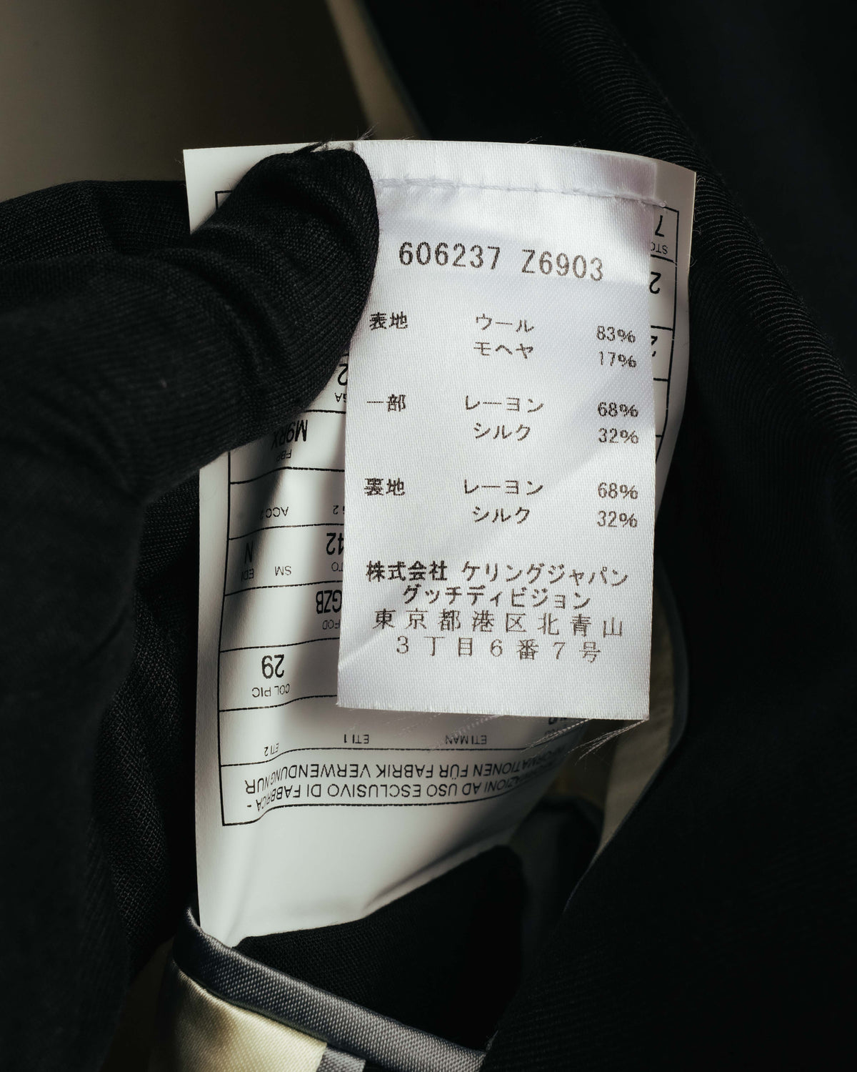 品番606237 Z6903、表地ウール83パーセント・モヘア17パーセント、裏地および一部レーヨン68パーセント・シルク32パーセントを記した内タグのカット。株式会社ケリングジャパン（グッチディビジョン）の表記も確認できる。