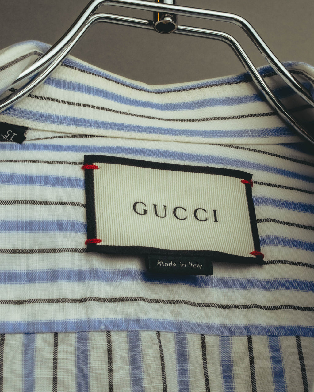 襟裏に配された、ブラックの縁取りと赤いステッチを用いたアイボリーのGUCCIタグ。下部にはMade in Italyの表記を確認できるカットです。