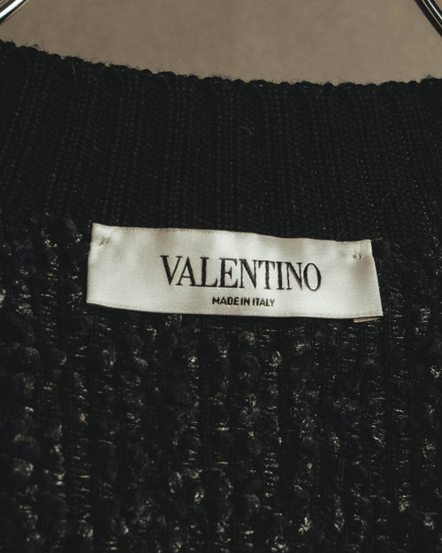襟元に配された「VALENTINO MADE IN ITALY」表記のネームタグ。ブラックのループ状の凹凸を持つニット地も確認できるカット。