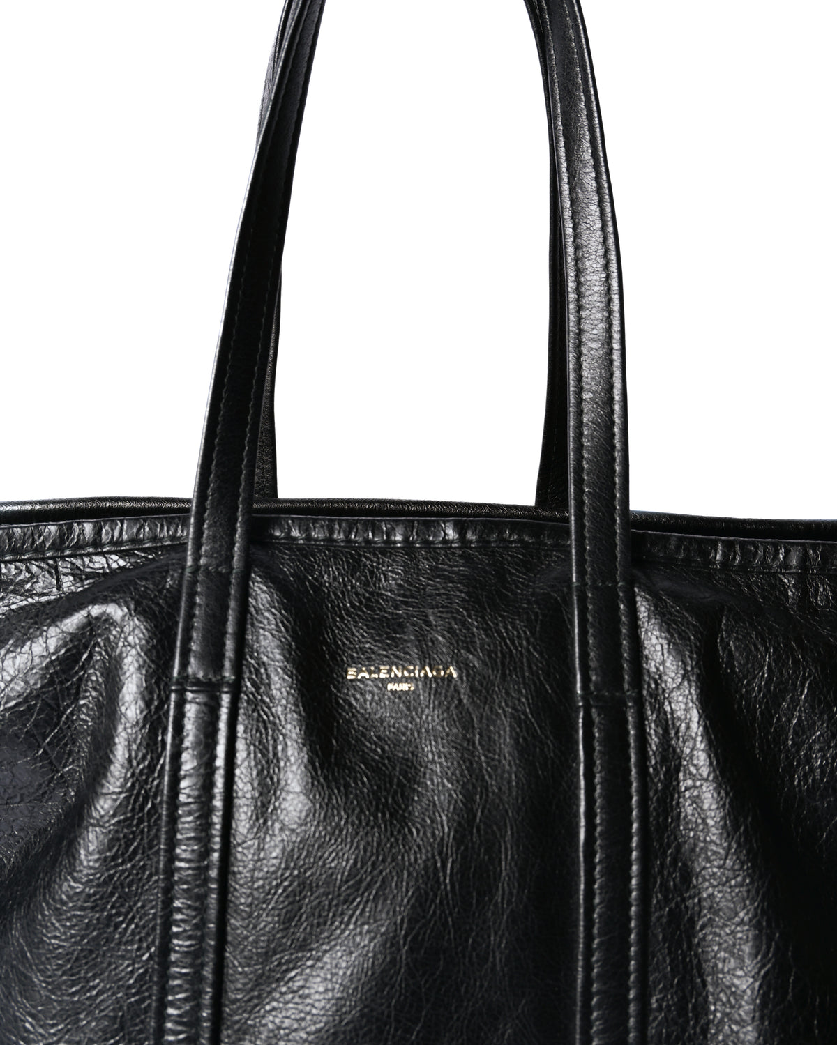 しなやかなブラックレザーのトップハンドルと、フロント上部にあしらわれた「BALENCIAGA PARIS」の箔押しロゴを捉えたディテールカット。ストライプ状のレザー切り替えと自然なシワ感も確認できます。