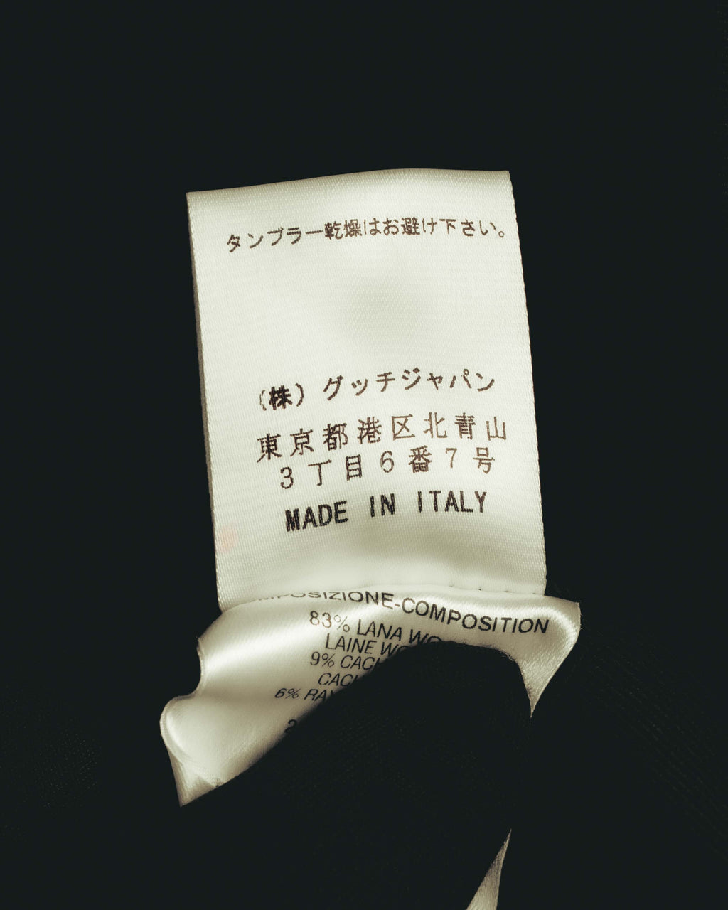 グッチジャパンの所在地と「MADE IN ITALY」表記が確認できる内側の品質表示タグ。下部にウール83%をはじめとする混紡素材の表記が見えるカット。