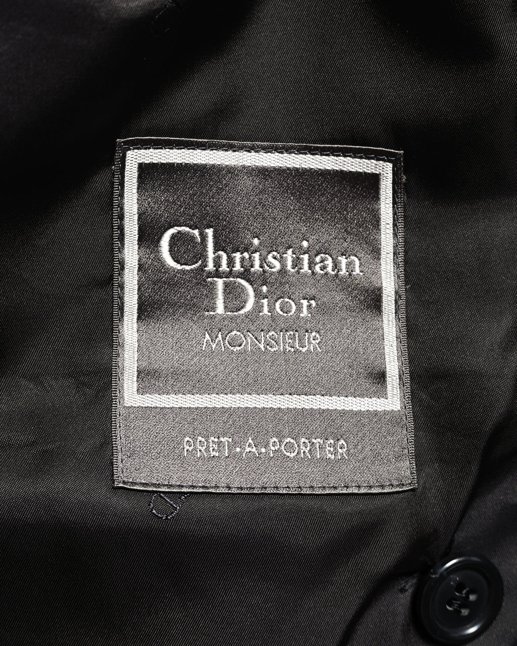内側に配された「Christian Dior MONSIEUR」「PRET-A-PORTER」表記のブランドタグ。ブラックの裏地に縫い付けられたタグのクローズアップです。