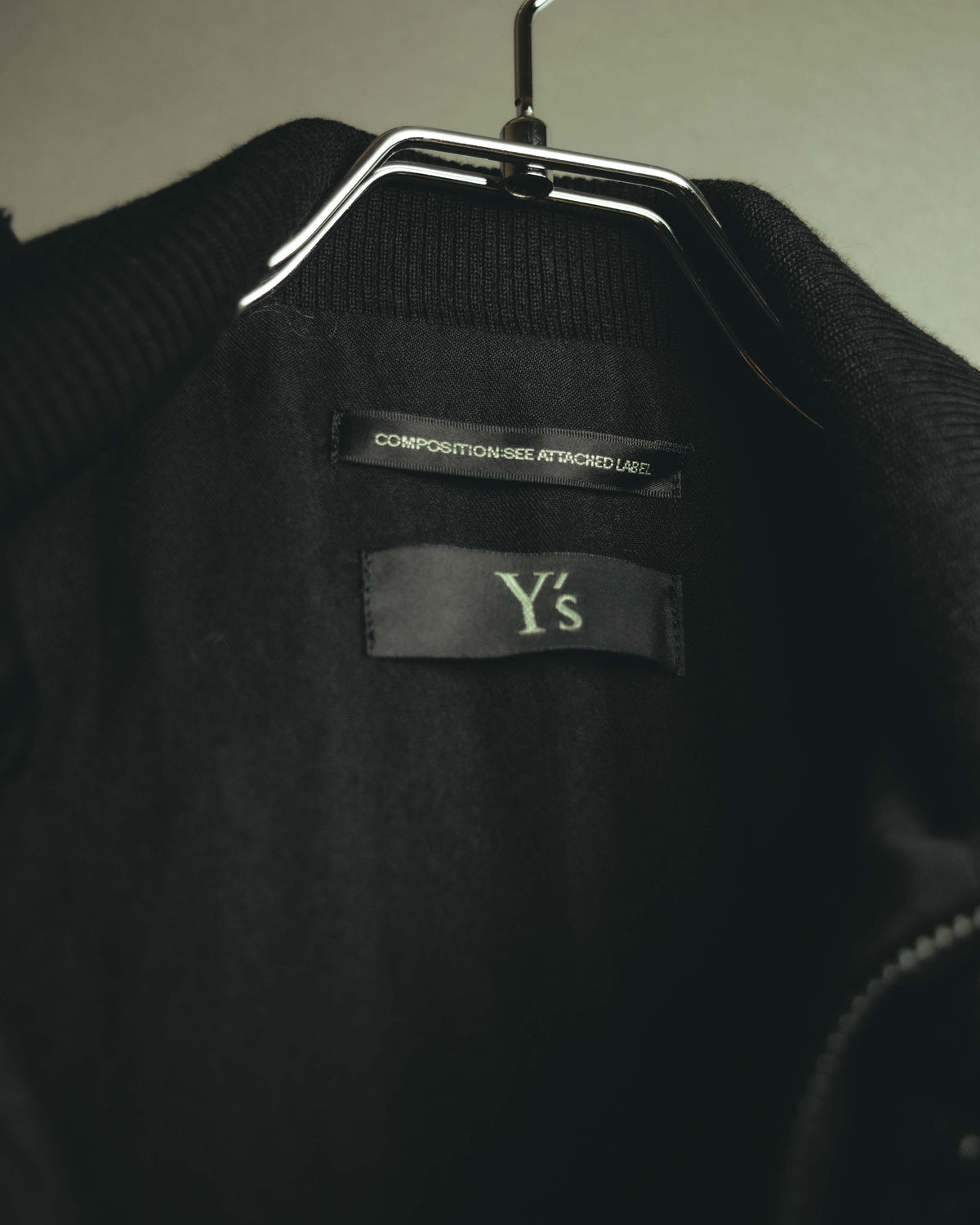 首元内側に配された「Y’s」ブランドタグのカット。高さを持たせたブラックのリブスタンドカラーと、内側のブラックの身頃をあわせて確認できます。