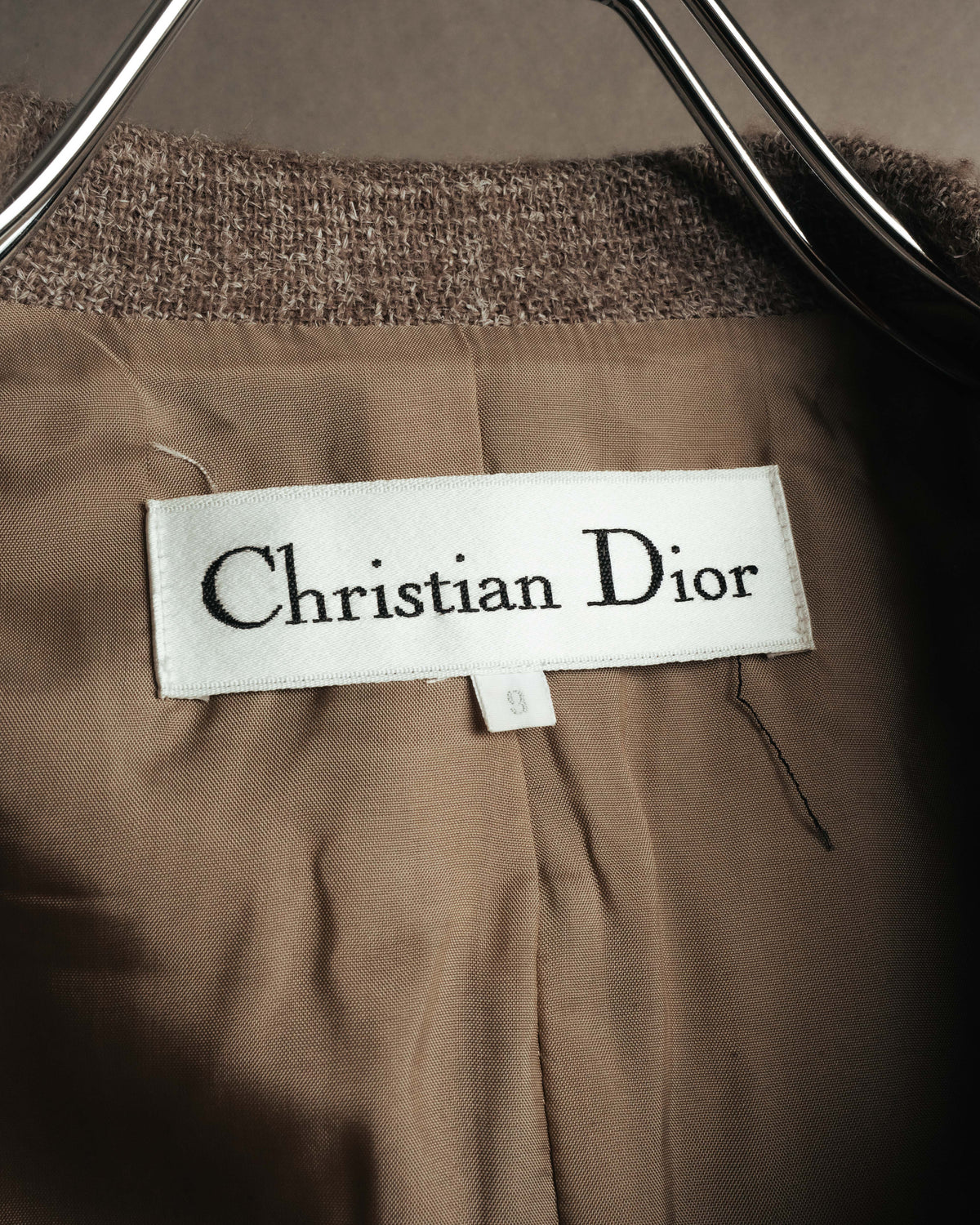襟元に配された、セリフ書体の「Christian Dior」織りタグを捉えたカット。総裏仕立てのキュプラ裏地とサイズ表記も確認できます。