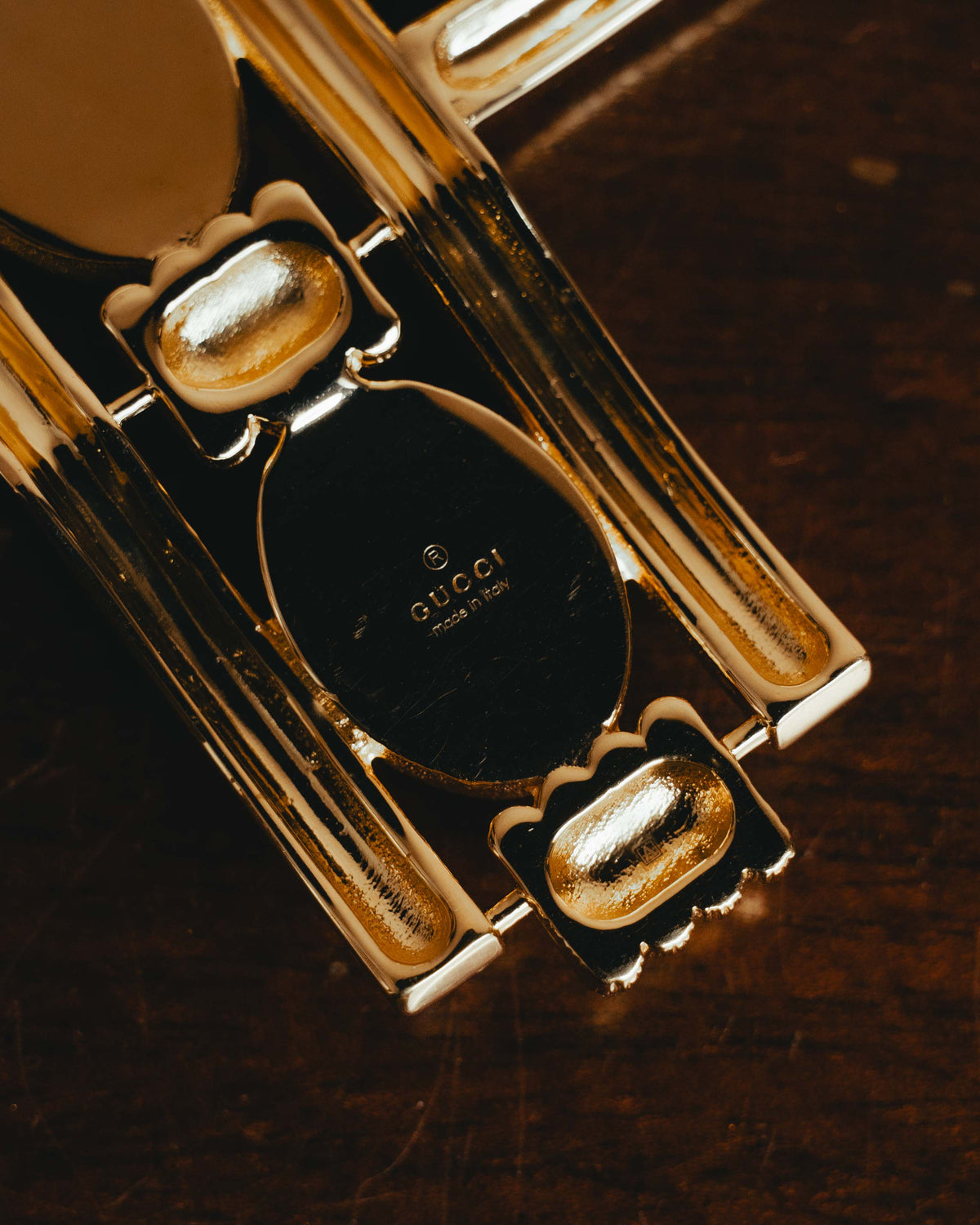 裏面に配された楕円形プレートのGUCCIおよびmade in Italy刻印と、長いピン軸を固定する回転式セーフティークラスプを捉えたディテールカット。