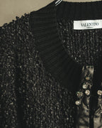 襟元のVALENTINO MADE IN ITALYネームと、ループ状の凹凸を持つブラックの編地を捉えたディテールカット。前立てには柔らかなブラックレザーと、爪留め状のクリアストーンが確認できます。