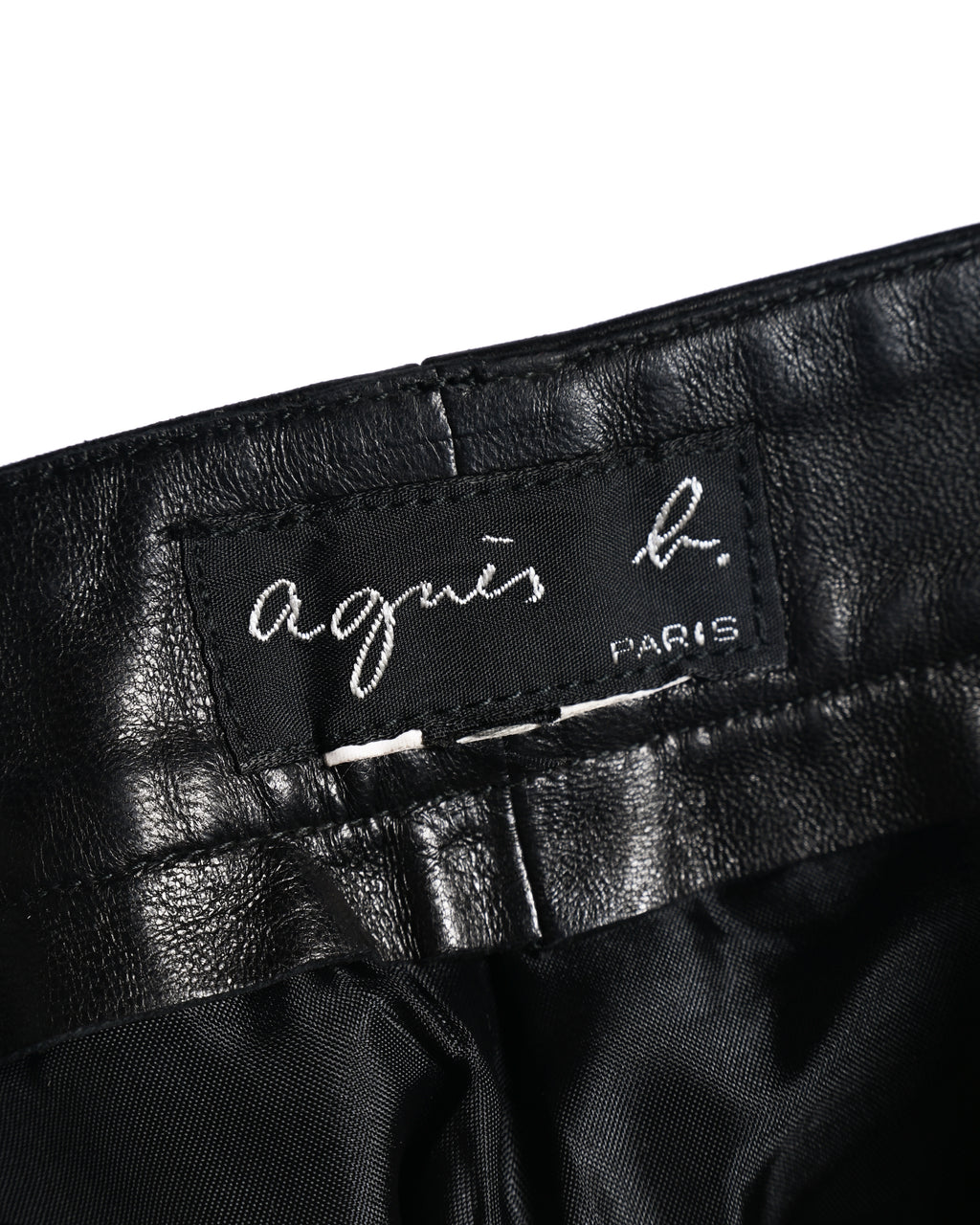 ウエスト内側に縫い付けられた「agnès b. PARIS」表記のブランドタグ。ブラックレザーの裏側とライニングの質感も確認できるカット。