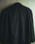 背面から捉えたジャケット全体のカット。ブラックとチャコールグレーを重ねた細かな格子状のチェック柄と、肩から裾へ落ちるシルエットが確認できます。