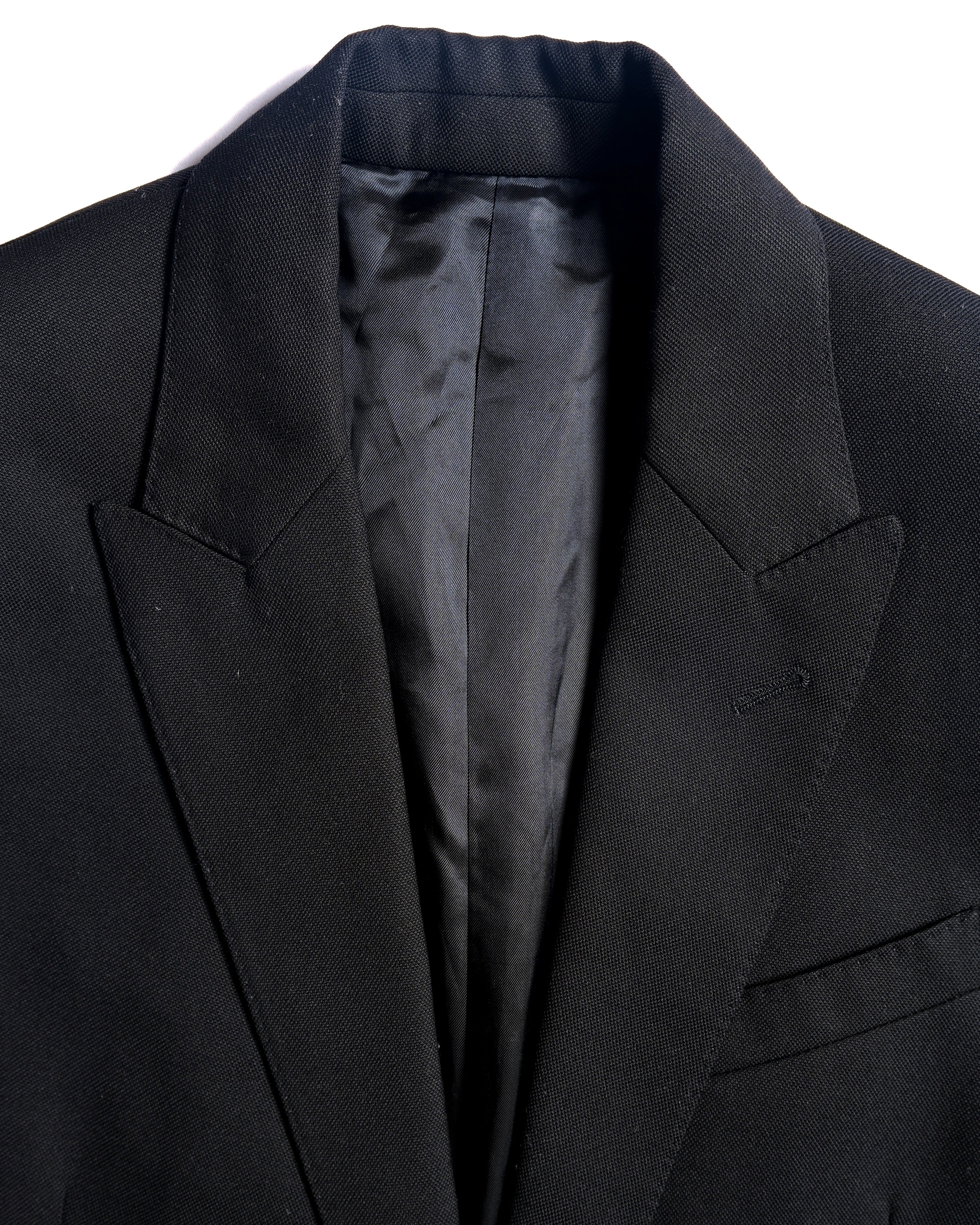 シャープに尖ったピークドラペルと、深めに取られたVゾーンを捉えたフロント上部のディテールカット。表地の細かな織りと、内側の滑らかな裏地も確認できます。