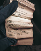 素材表記とケア表記が確認できる内側の洗濯表示タグ。裁ち切り部分のほつれや糸切れが生じる旨を記載した注意書きも写るカット。