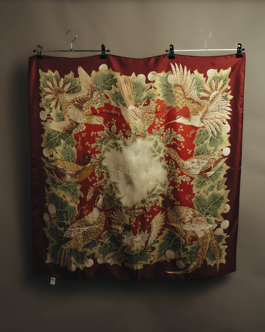 深みのあるボルドーを基調に、羽ばたく鳥や枝に佇む鳥、葉や木の実を配したスクエア全体のカット。中央にはセピア調の狩猟風景が配されています。