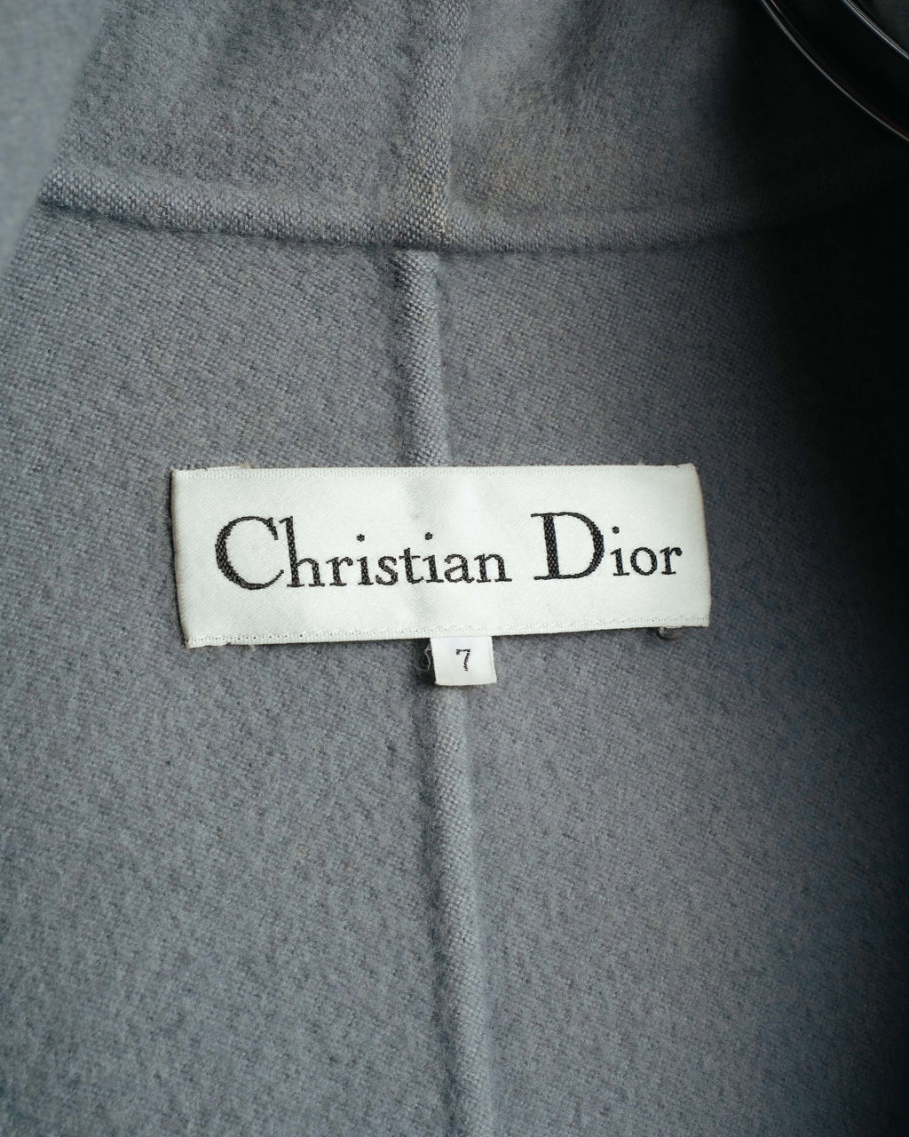 白地に黒のセリフ体で織られたChristian Diorのブランドラベルと、表記サイズ7のタグを捉えた内側のカット。淡いグレーのショールカラー内側の起毛感ある生地も確認できます。