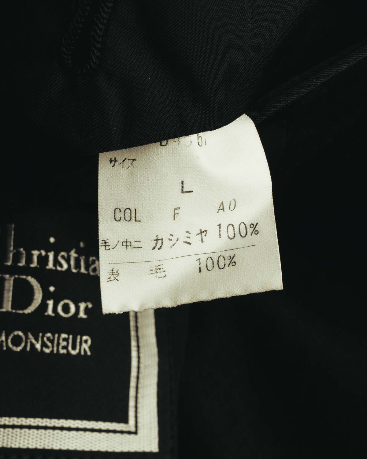 内側に配されたChristian Dior MONSIEURの織りネームと、日本語による品質表示タグのクローズアップ。品質表示には表地カシミヤ100%の表記が確認できます。