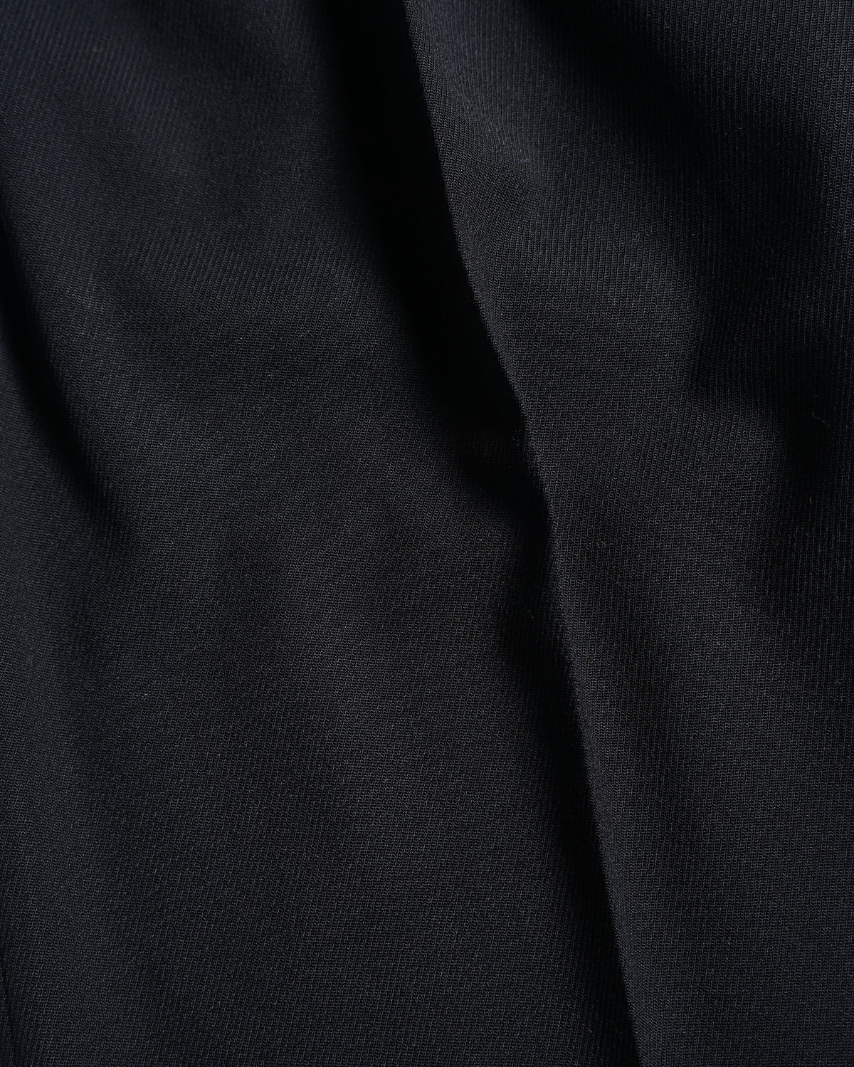 深みのあるブラックの生地表面と、落ち感によって生まれる陰影を捉えた素材アップ。細かな織りとしなやかな質感が確認できます。