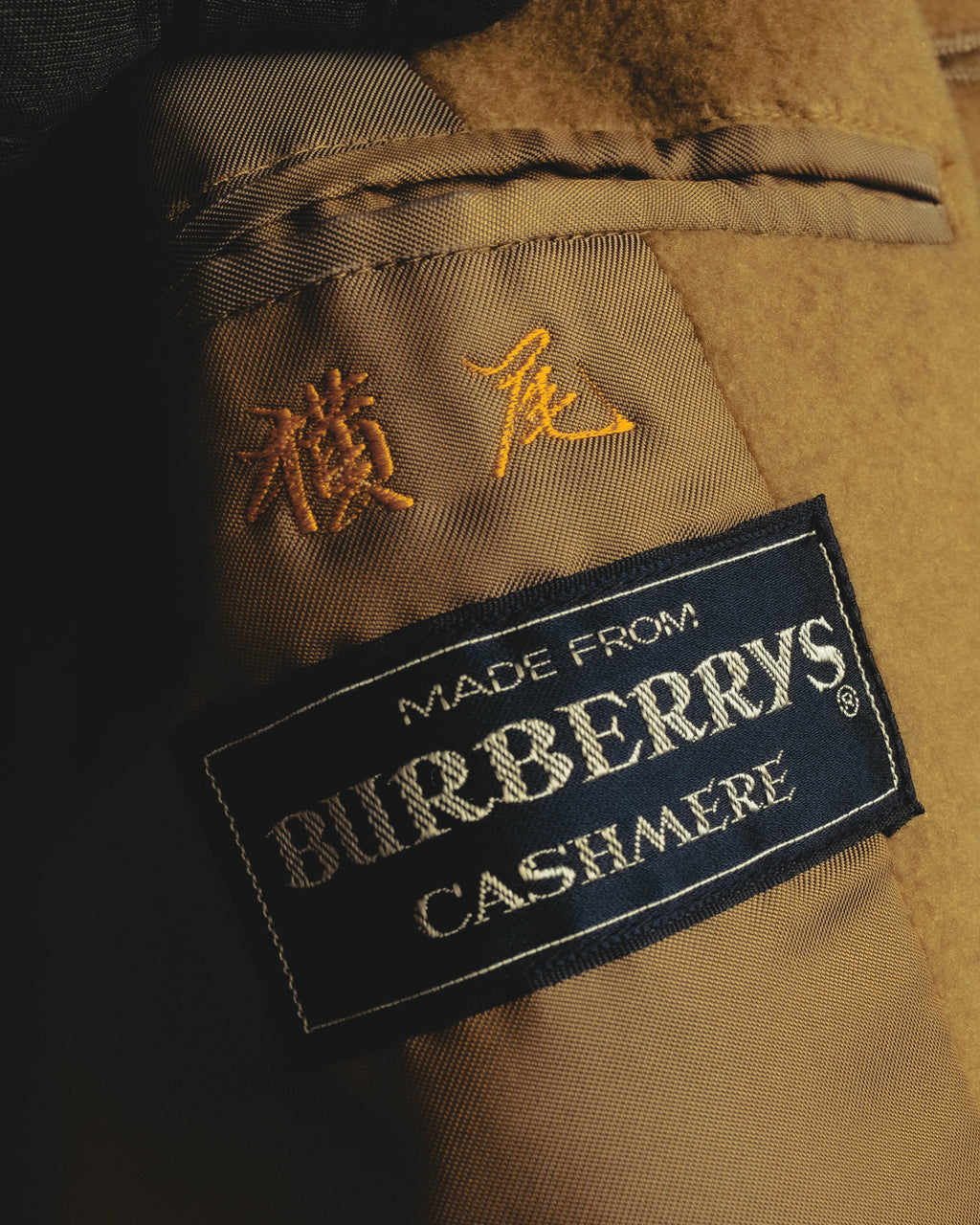 内側に配された「BURBERRYS CASHMERE」表記のブランドタグと、その上部に残る横尾と読めるネーム刺繍のクローズアップ。