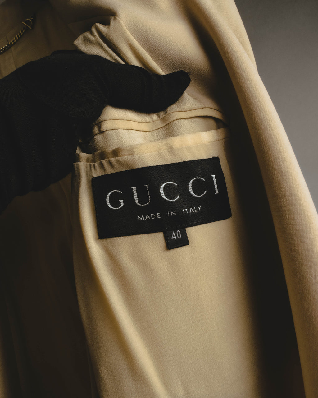 首元内側に配されたブラックの織りネーム。「GUCCI MADE IN ITALY」表記とサイズタグ、ゴールドカラーのネックチェーンを確認できるカット。